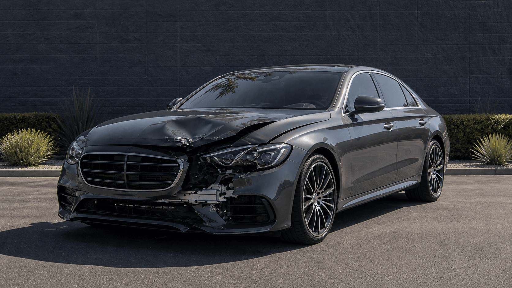 Representative dark gray sedan with visible front-end collision damage